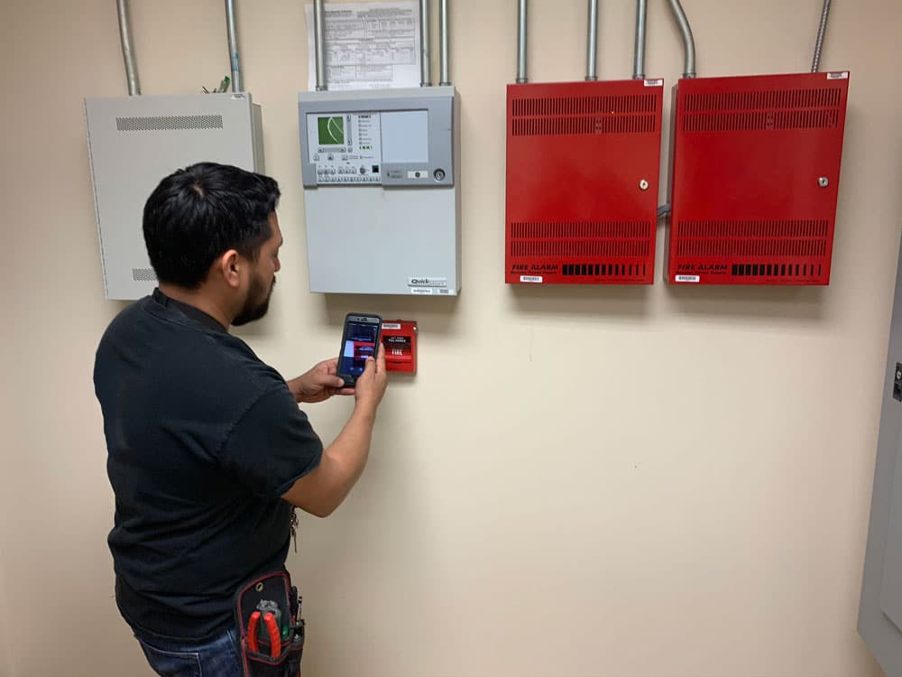 a person working with an app next to a fire panel